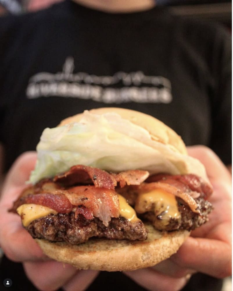 Bacon cheeseburger held in two hands