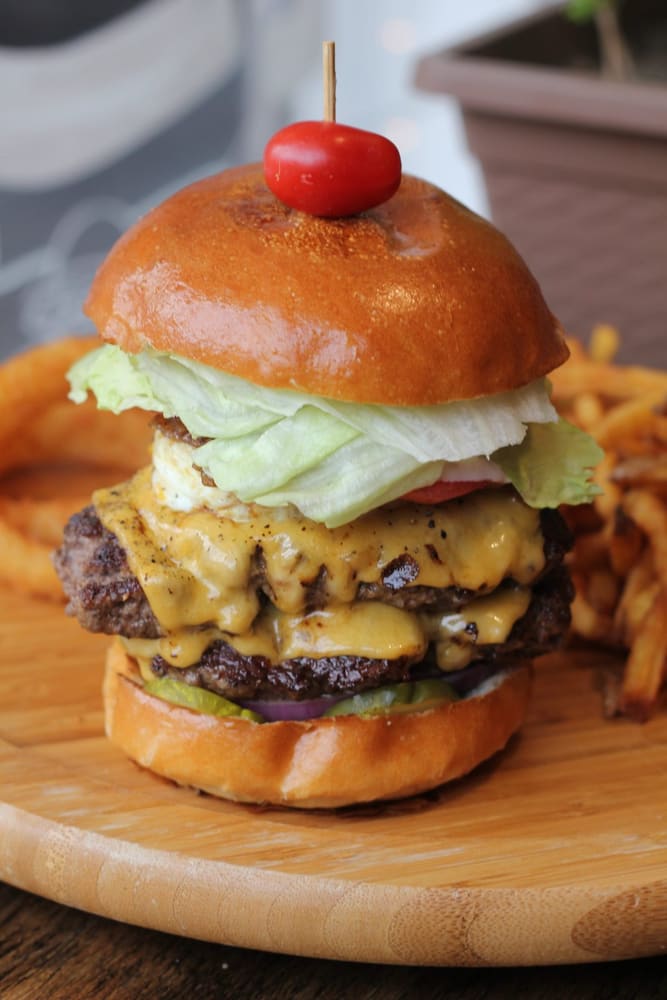 Big Boy burger topped with a fried egg on a wooden board