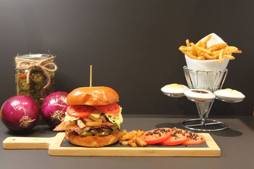Hot Hawaiian burger plated with fries, dips and pickled jalapenos