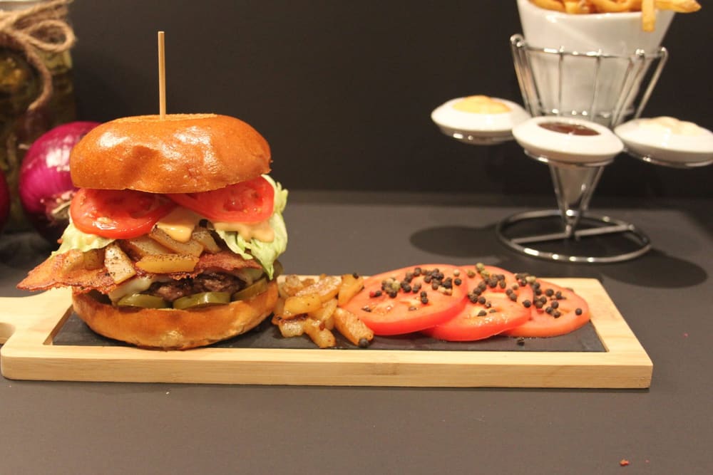 Hot Hawaiian burger on a board with fries and sliced tomato